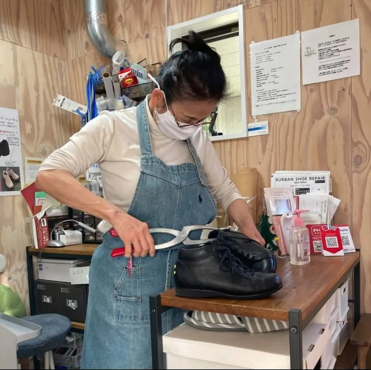 ANDANTINO店内で五十嵐洋子が黒い革靴を調整している様子